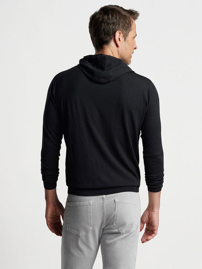 Man wearing a Peter Millar Excursionist Flex Popover Hoodie in Black and light gray pants viewed from the back.