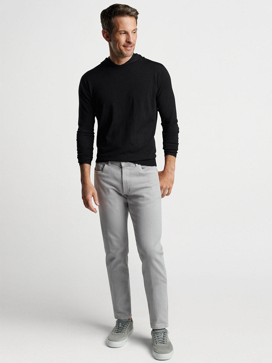 Man posing in a Peter Millar Excursionist Flex Popover Hoodie in Black and gray pants with a neutral expression.
