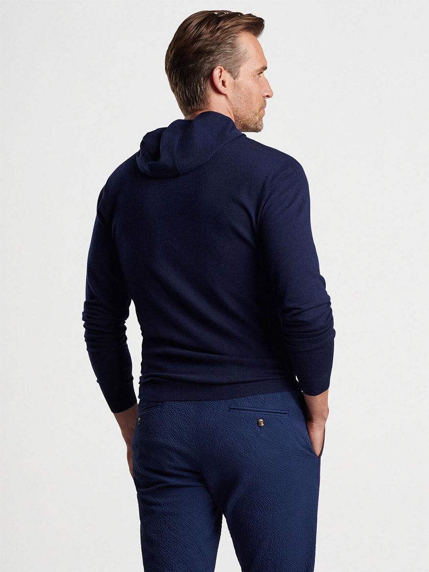 Man wearing a Peter Millar Excursionist Flex Popover Hoodie in Navy and matching pants, made from performance Merino wool yarn, viewed from behind.