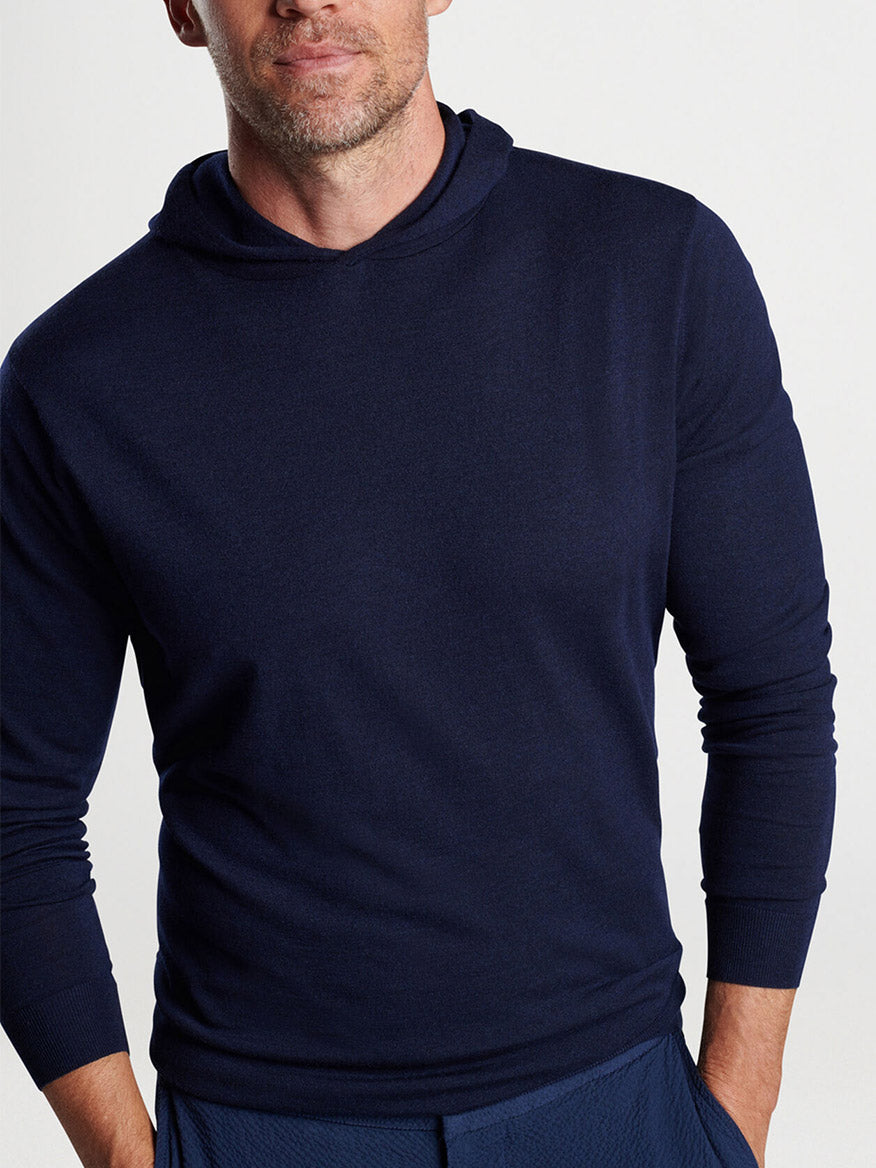 Man wearing a Peter Millar Excursionist Flex Popover Hoodie in Navy made from Merino wool.