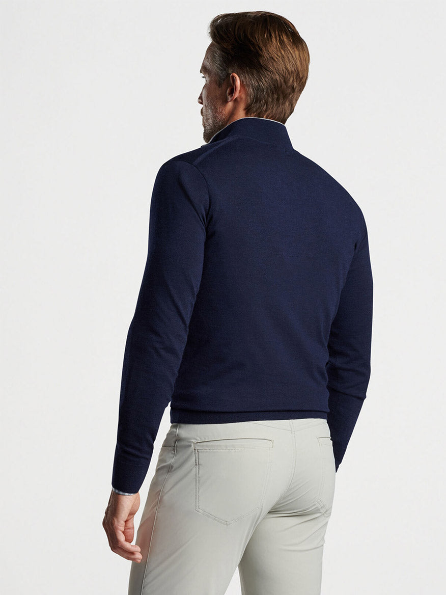 Man wearing a Peter Millar Excursionist Flex Quarter-Zip in Navy and light gray pants standing with his back to the camera.