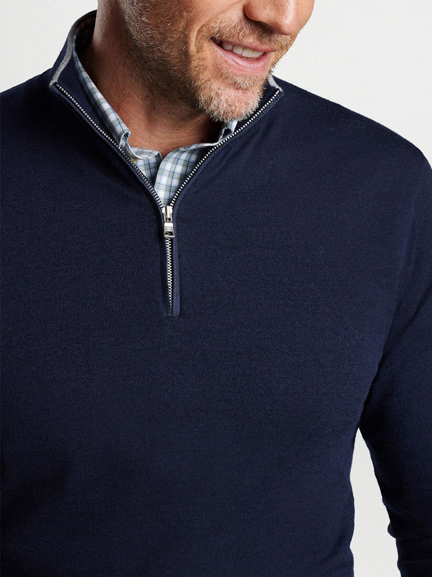 Smiling man wearing a Peter Millar Excursionist Flex Quarter-Zip in Navy over a checkered shirt.