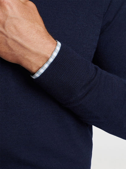 A person wearing a Peter Millar Excursionist Flex Quarter-Zip in Navy with a tailored fit shirt underneath, the shirt's cuff visible at the wrist.