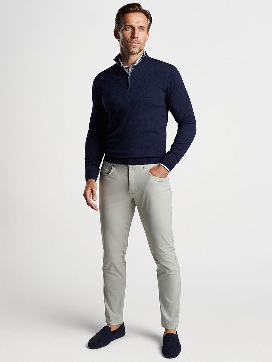 Man posing in a Peter Millar Excursionist Flex Quarter-Zip in Navy, light grey trousers, and blue loafers.