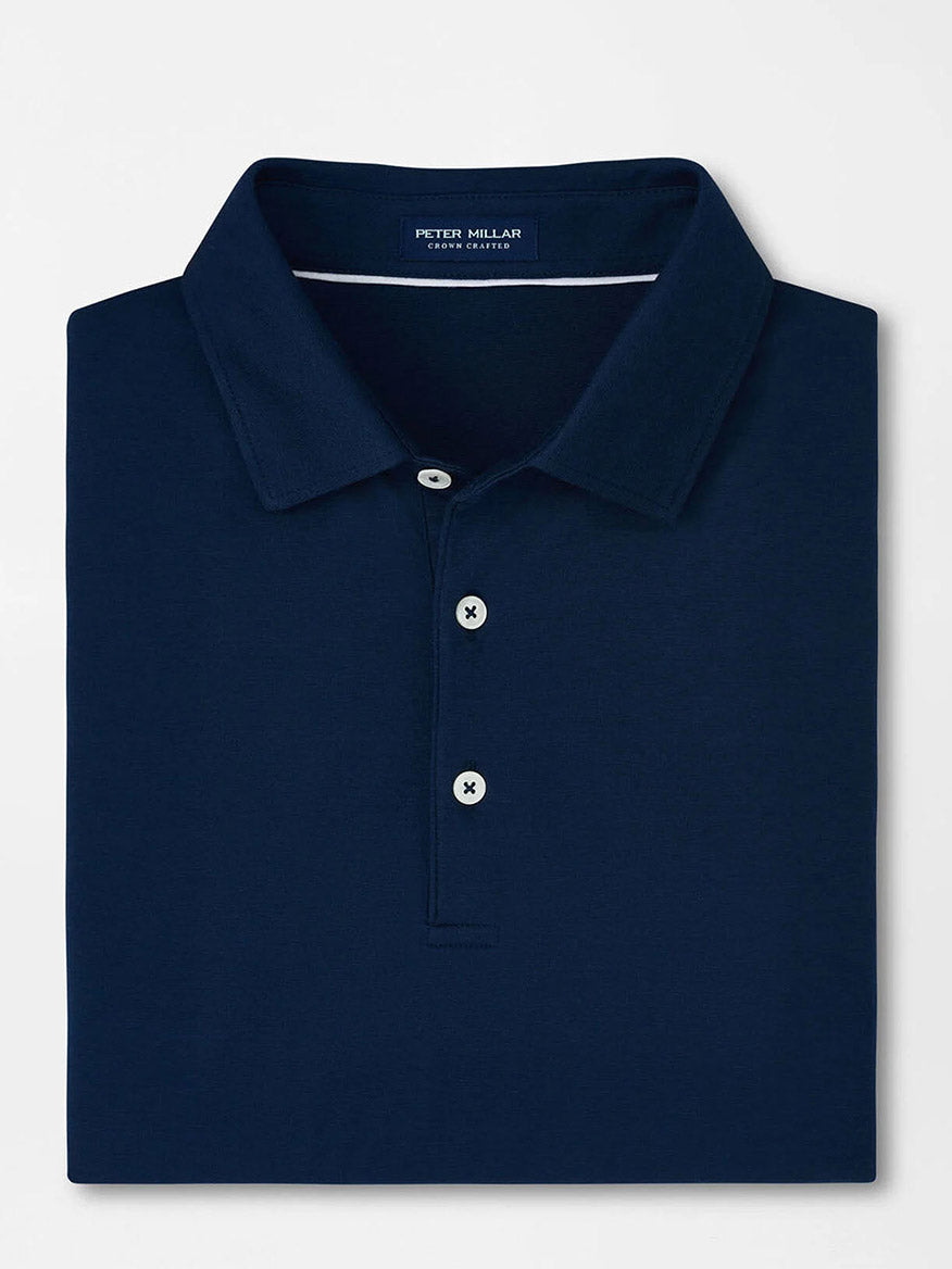 Folded Peter Millar Excursionist Flex Polo in Atlantic Blue, showcasing a white button placket and crafted from cotton-based jersey knit for ultimate comfort and style, displayed on a pristine white background.