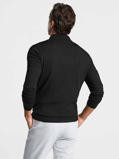 A man viewed from the back wearing a Peter Millar Excursionist Flex Quarter-Zip in Black sweater and white pants.