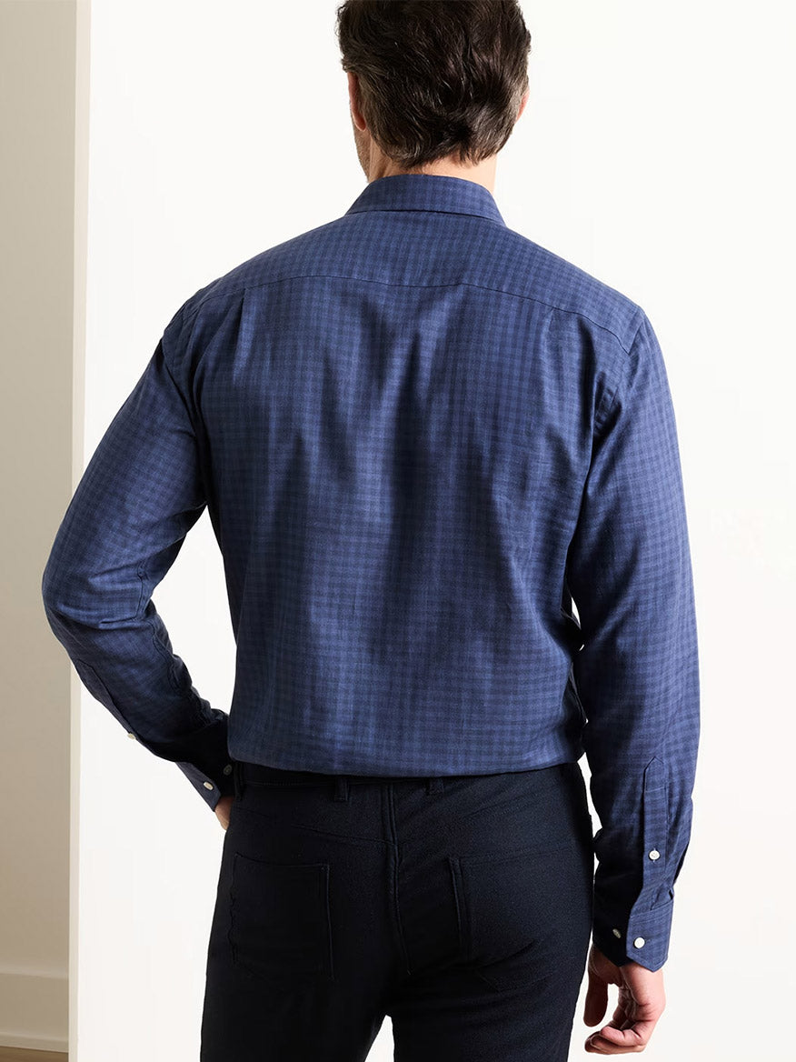 A person stands with their back to the camera, wearing the Peter Millar Felix Cotton Sport Shirt in Navy and dark pants against a plain, light-colored background.