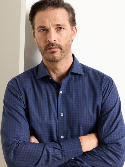 A man with light brown hair and a beard stands with his arms crossed against a light background, wearing the Peter Millar Felix Cotton Sport Shirt in Navy.