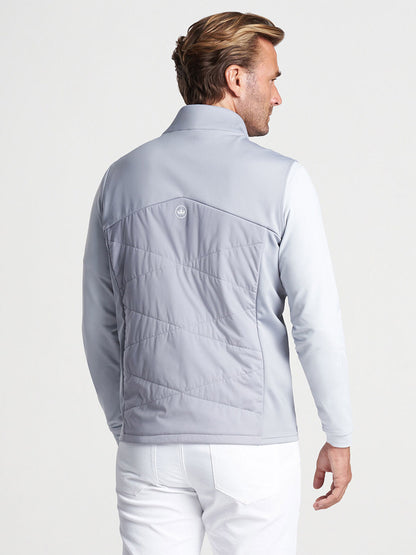 A man viewed from behind wearing a Peter Millar Fuse Hybrid Vest in Gale Grey, and white pants.