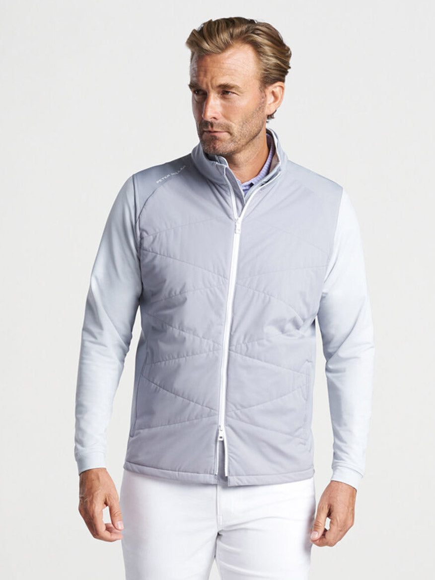 Man wearing a Peter Millar Fuse Hybrid Vest in Gale Grey and white pants.
