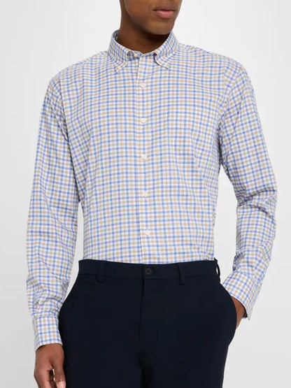 A person is wearing the Peter Millar Gardner Crown Lite Cotton-Stretch Sport Shirt in Blue Freesia, a blue and beige checkered long-sleeve button-up shirt in a classic fit, paired with dark pants.