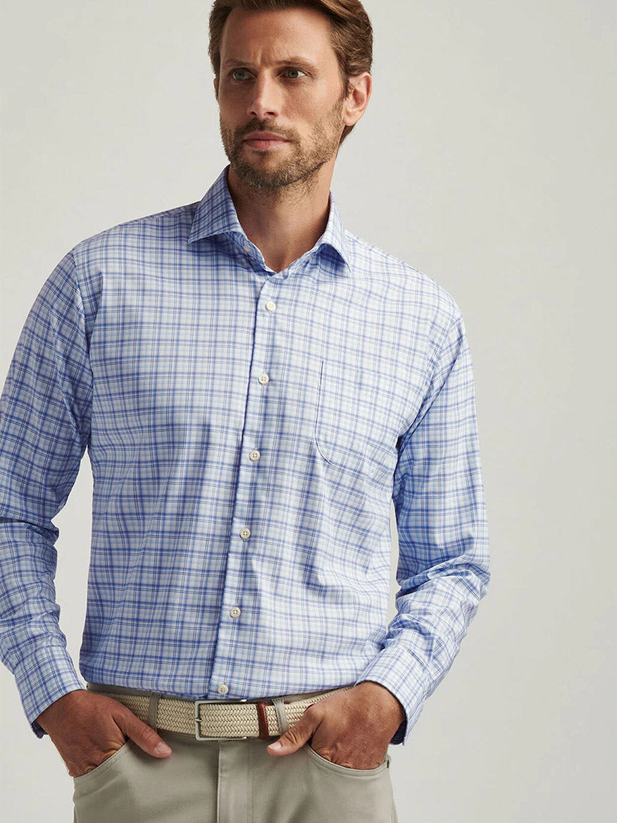 A man wearing a Peter Millar Garrow Crown Lite Cotton-Stretch Sport Shirt in Blue Freesia and beige pants stands against a neutral background.