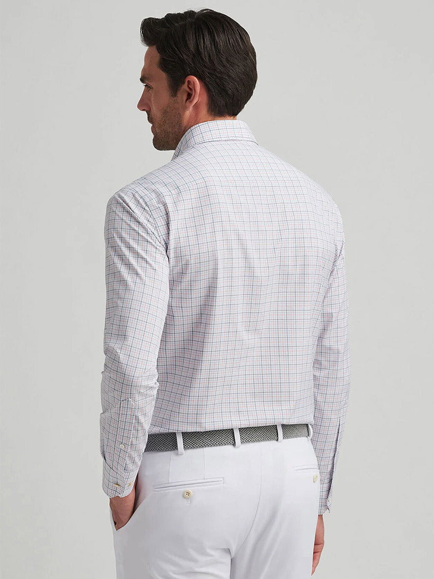 A man in a Peter Millar Getz Performance Poplin Sport Shirt (Navy) and white pants stands facing away, prepared for a day outside with UPF 50+ sun protection.