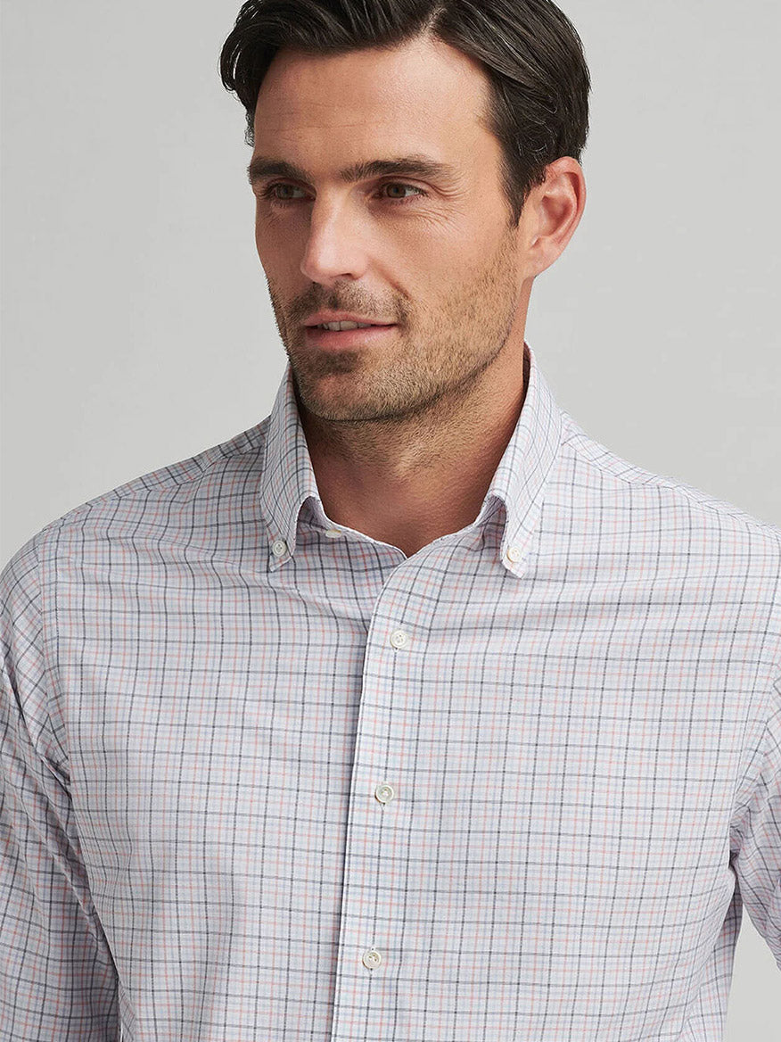 A man in a Peter Millar Getz Performance Poplin Sport Shirt in Navy, featuring UPF 50+ sun protection, looks to the side against a plain background.