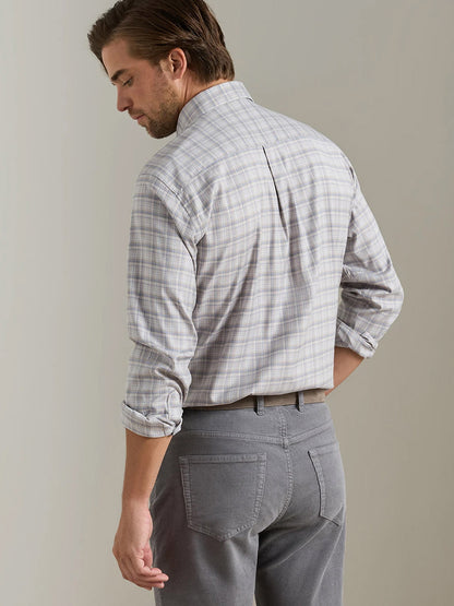 A man stands facing away against a plain background, wearing the Peter Millar Griffin Crown Soft Twill Sport Shirt in Battleship Grey with rolled sleeves and gray pants.