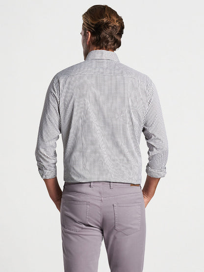 A man standing with his back towards the camera, wearing a Peter Millar Hanford Performance Twill Sport Shirt in Cottage Blue and light purple pants.