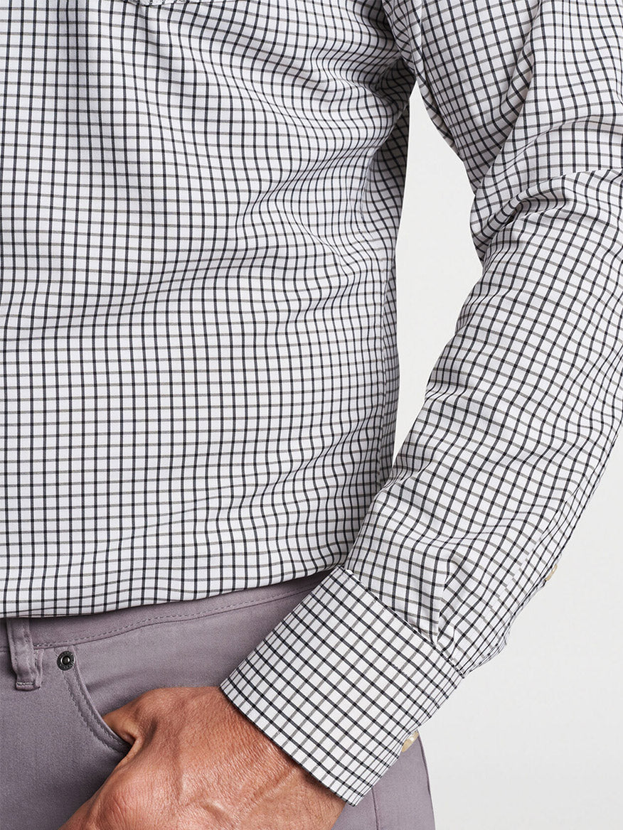 Close-up of a person dressed in a Peter Millar Hanford Performance Twill Sport Shirt in Cottage Blue with a rolled-up sleeve, tucked into gray pants.