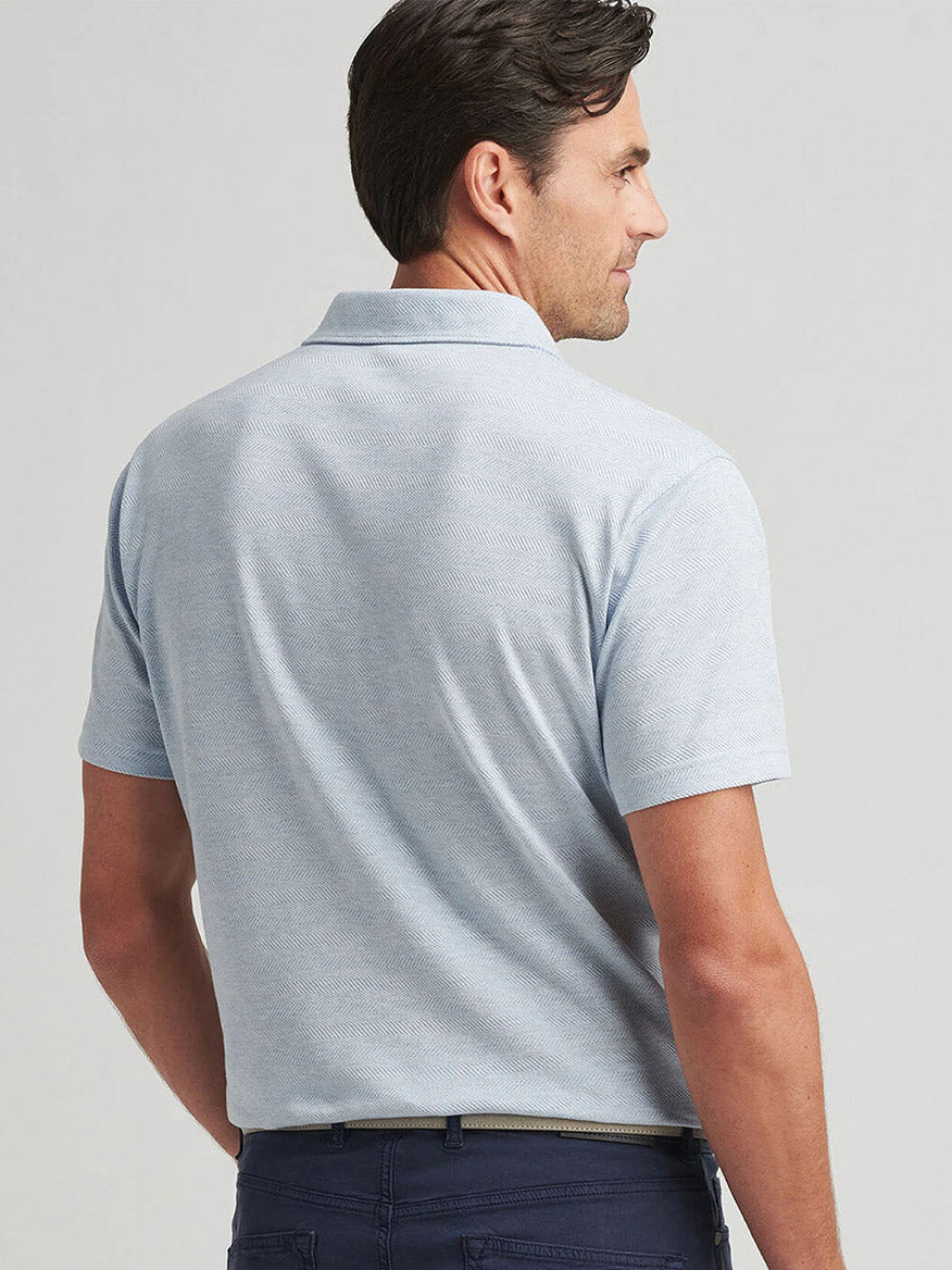 A man is shown from the back wearing a Peter Millar Harris Herringbone Knit Polo in Blue Frost, featuring a cotton-blend and tailored fit, paired with dark pants.