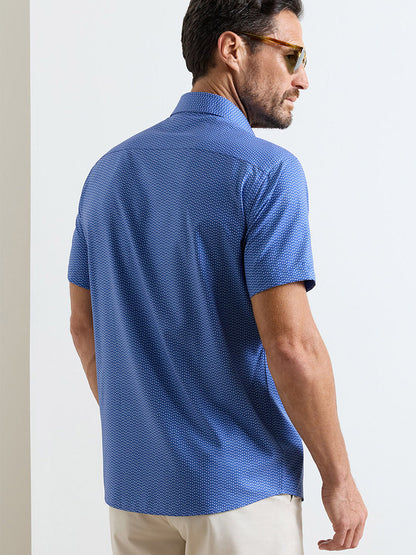 A man in sunglasses and a Peter Millar Jackson Performance Poplin Sport Shirt in Windsor Blue with UPF 50+ sun protection stands facing away from the camera.