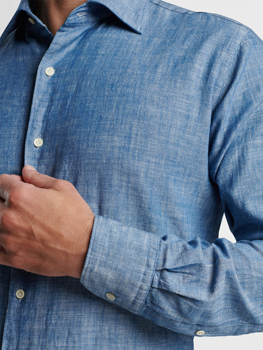 Man wearing a blue Peter Millar Japanese Selvedge Sport Shirt in Light Chambray with his hand on his cuff.