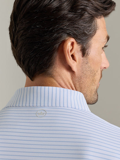 A man with short brown hair, shown from behind, wears the Peter Millar Keynote Performance Jersey Polo in White—featuring light blue and white stripes, a collared design, and UPF 50+ sun protection for all-day comfort.