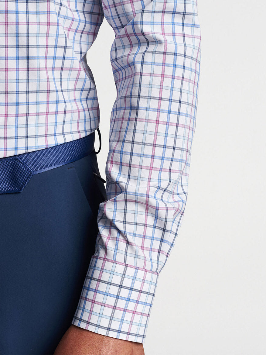 A person in a Peter Millar Kimball Performance Poplin Sport Shirt in Valencia with rolled-up sleeves tucked into navy trousers, featuring UPF 50+ performance fabrication.