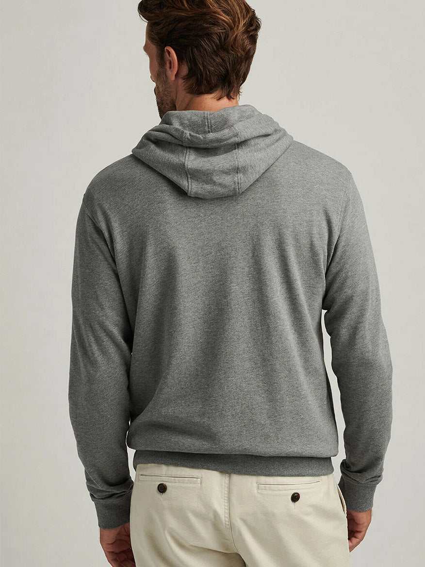 A person is pictured from the back in the Peter Millar Lava Wash Hoodie in Gale Grey and light-colored pants, set against a plain background to showcase its super-soft cotton-modal comfort for everyday wear.