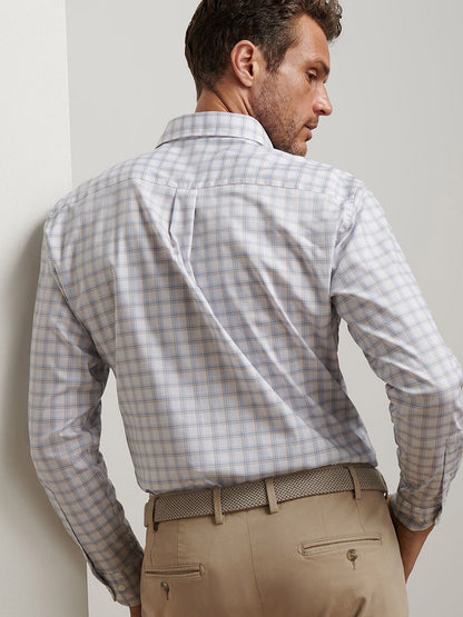 Man facing away, wearing a Peter Millar Lenox Crown Lite Cotton-Stretch Sport Shirt in White and beige pants with a woven belt, standing near a white wall.
