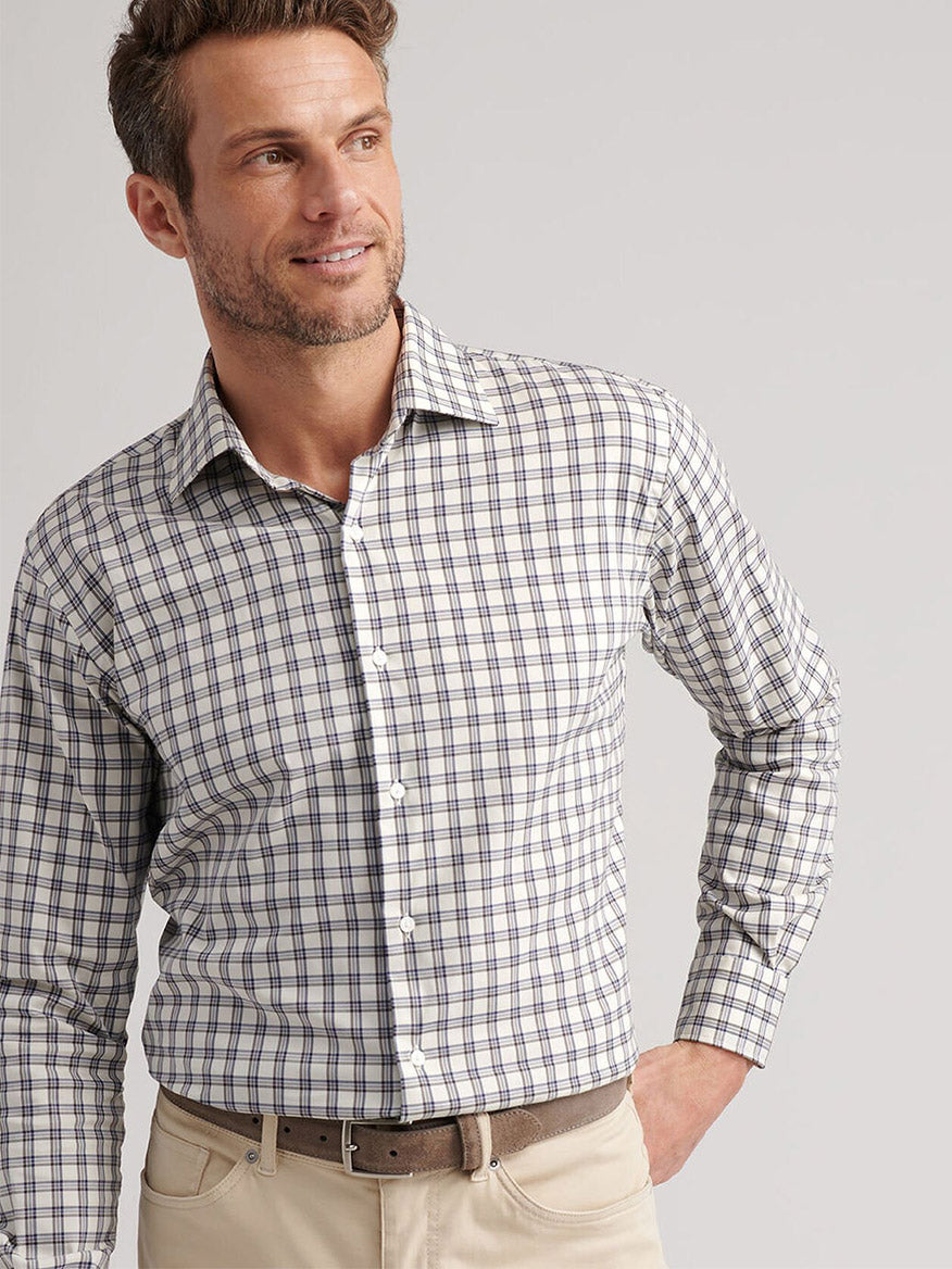A man wears the Peter Millar Lenox Crown Lite Cotton-Stretch Sport Shirt in Winter Ivory with beige pants, standing against a plain background with one hand on his hip.