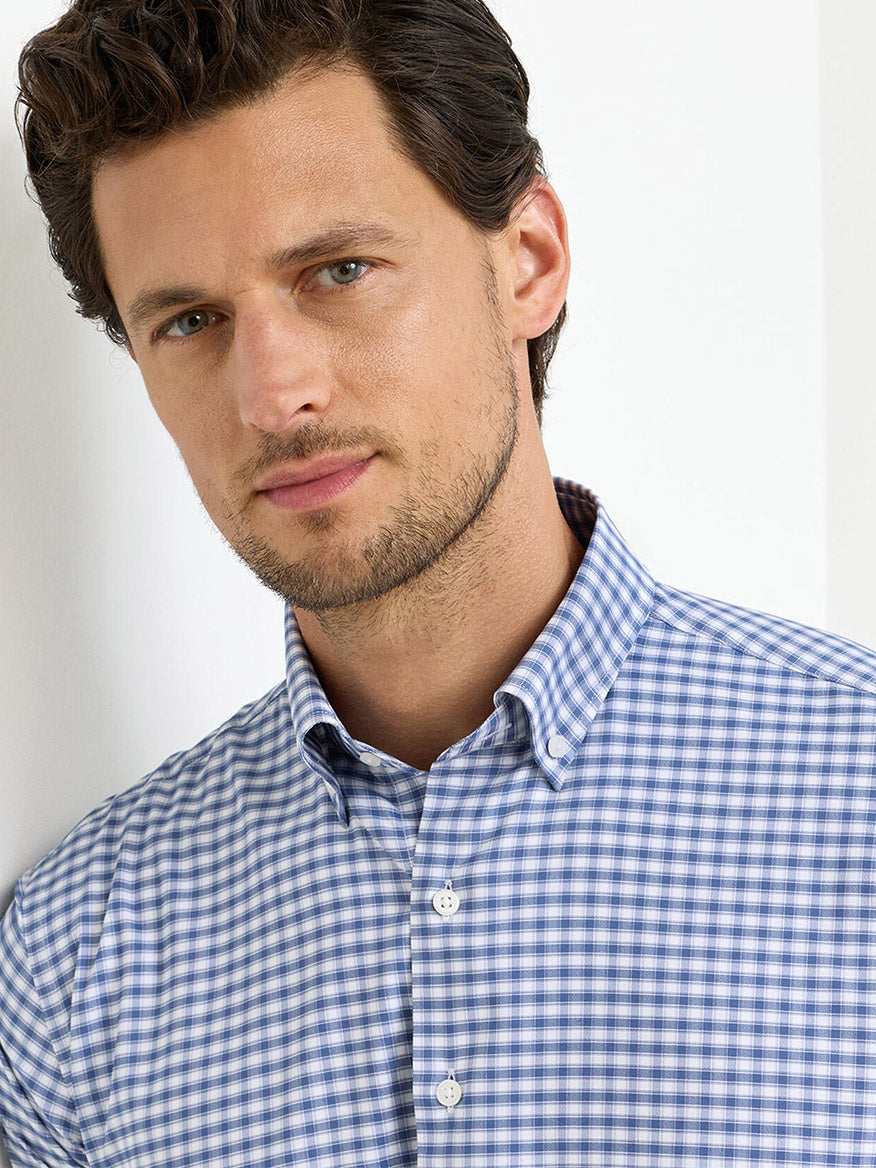 A man wearing the Peter Millar Lewis Performance Twill Sport Shirt in Windsor Blue stands against a white background, looking at the camera.