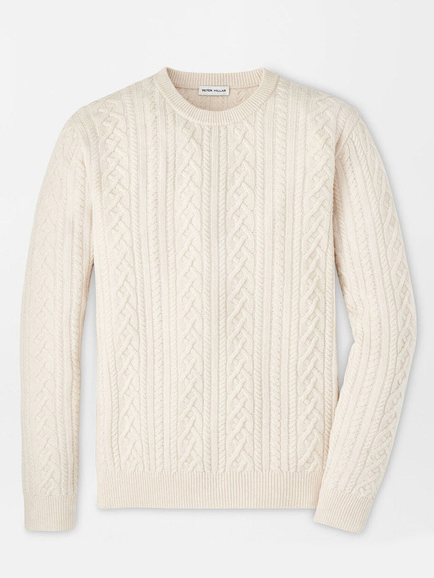 The Peter Millar Crescent Ridge Cable Crew in Winter Ivory, an elegant long-sleeve cable-knit sweater made from Merino wool, is showcased on a plain white background. Ideal for three-season wear, this piece seamlessly blends classic style with comfort.