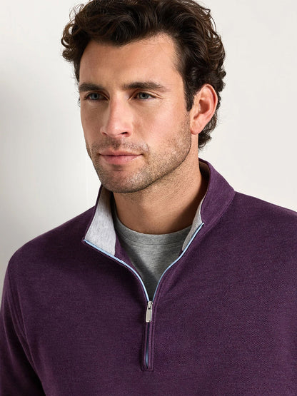 A man with short brown hair and light stubble wears the Peter Millar Crown Comfort Pullover in Grapeseed—a lightweight, four-way stretch quarter-zip—over a gray shirt, looking slightly to the side.