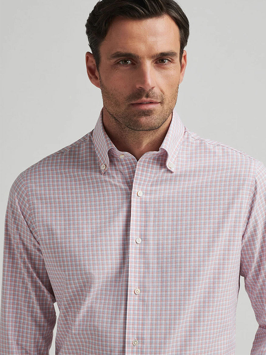 Someone in a Peter Millar Mingus Performance Poplin Sport Shirt in Pink Crepe stands against a plain background, enjoying UPF 50+ sun protection benefits.