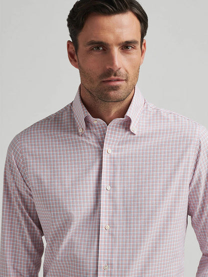 Someone in a Peter Millar Mingus Performance Poplin Sport Shirt in Pink Crepe stands against a plain background, enjoying UPF 50+ sun protection benefits.