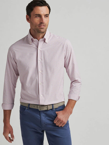 A man in a Peter Millar Mingus Performance Poplin Sport Shirt in Pink Crepe with UPF 50+ and blue trousers stands against a plain background.