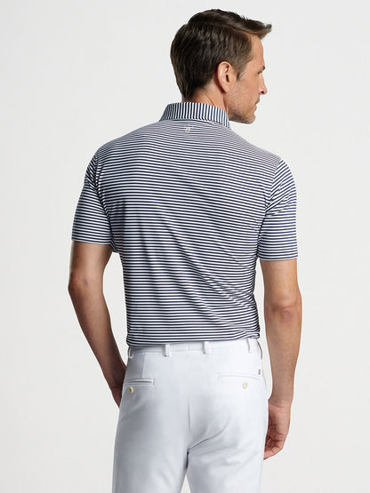 Man wearing a striped Peter Millar Mood Performance Mesh Polo in Navy and white trousers viewed from the back.