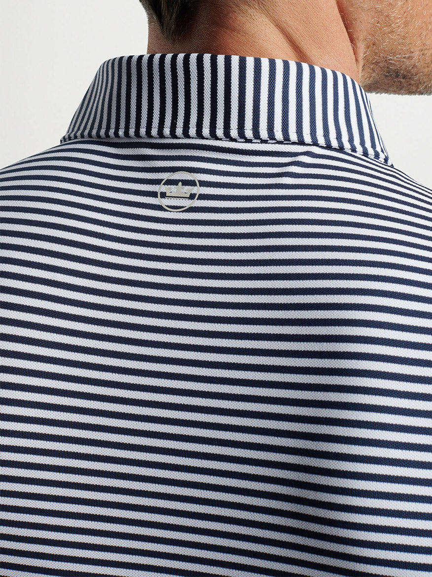 A close-up of a person wearing a Peter Millar Mood Performance Mesh Polo in Navy with a buttoned collar from the back.