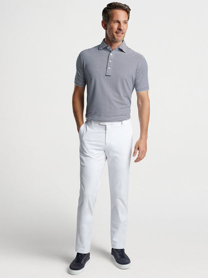 Man wearing a striped Peter Millar Mood Performance Mesh Polo in Navy and white trousers with dark shoes.