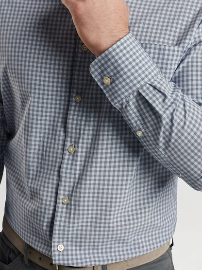 A person wearing the Peter Millar Murray Performance Poplin Sport Shirt in Navy is partially visible from the neck down. The shirt, made from easy-care performance fabric, features buttoned cuffs and a front pocket. The left hand is raised near the face.