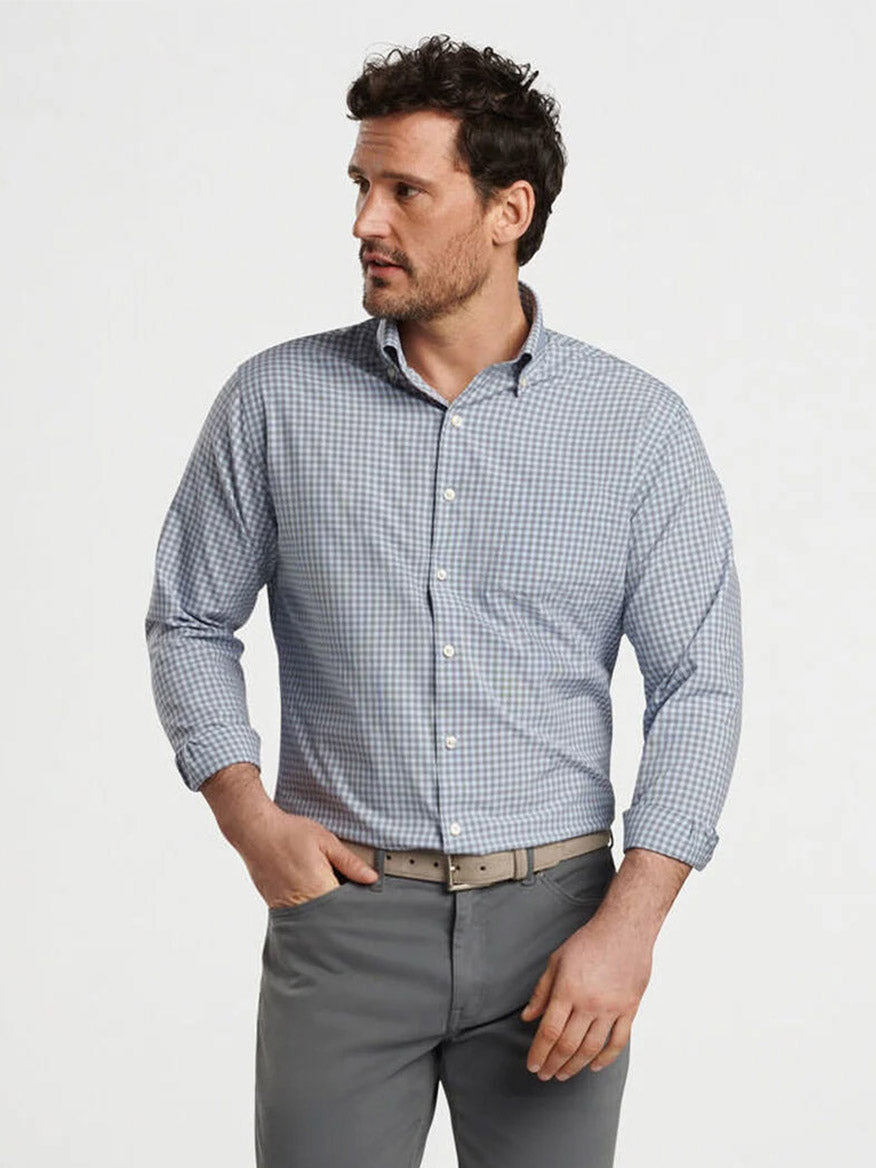 Man wearing a Peter Millar Murray Performance Poplin Sport Shirt in Navy with rolled-up sleeves and gray trousers, standing against a plain white background.