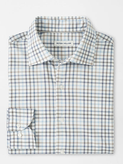A folded Peter Millar North Coast Crown Lite Cotton-Stretch Sport Shirt in Blue Haze features a blue, gray, and beige plaid. Made from easy-care twill with a classic fit, it includes the "Peter Millar" label inside.