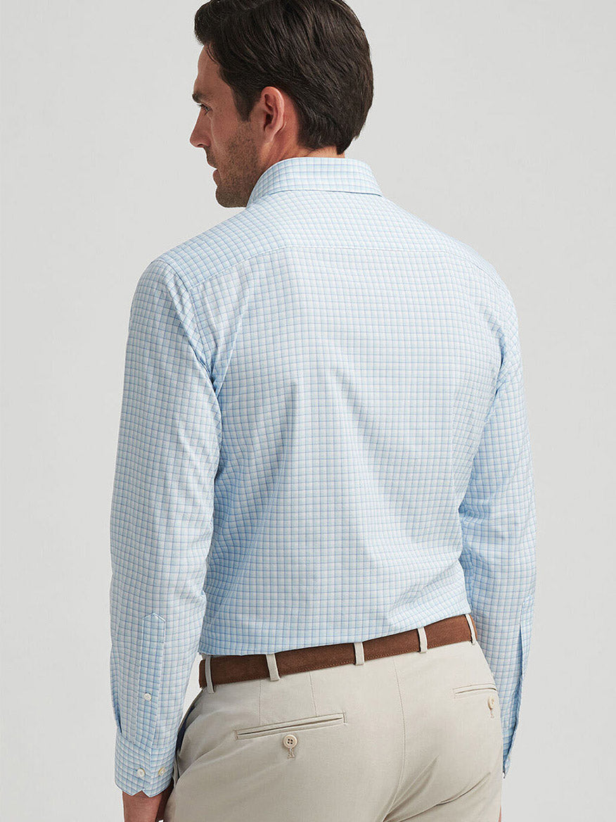 A man in a Peter Millar Parker Performance Poplin Sport Shirt in Blue Spruce, offering UPF 50+ sun protection, paired with beige pants, is viewed from behind. He has short dark hair.