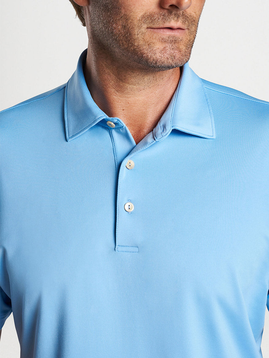 Man wearing a Peter Millar Solid Performance Jersey Polo in Cottage Blue [Sean Self Collar], designed for comfort on the golf course.