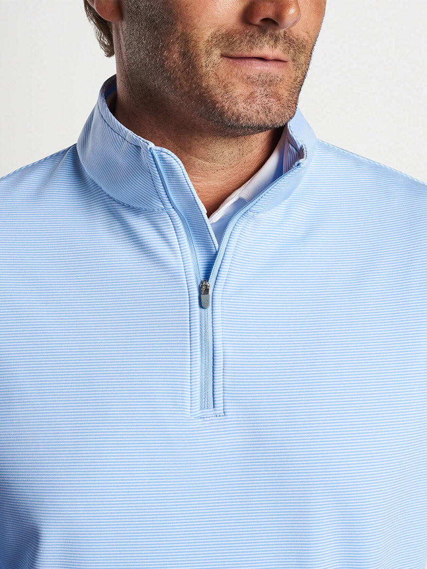 Man wearing a Peter Millar Perth Sugar Stripe Performance Quarter-Zip shirt in Cottage Blue/White, which is known for its performance-focused design and moisture-wicking properties.
