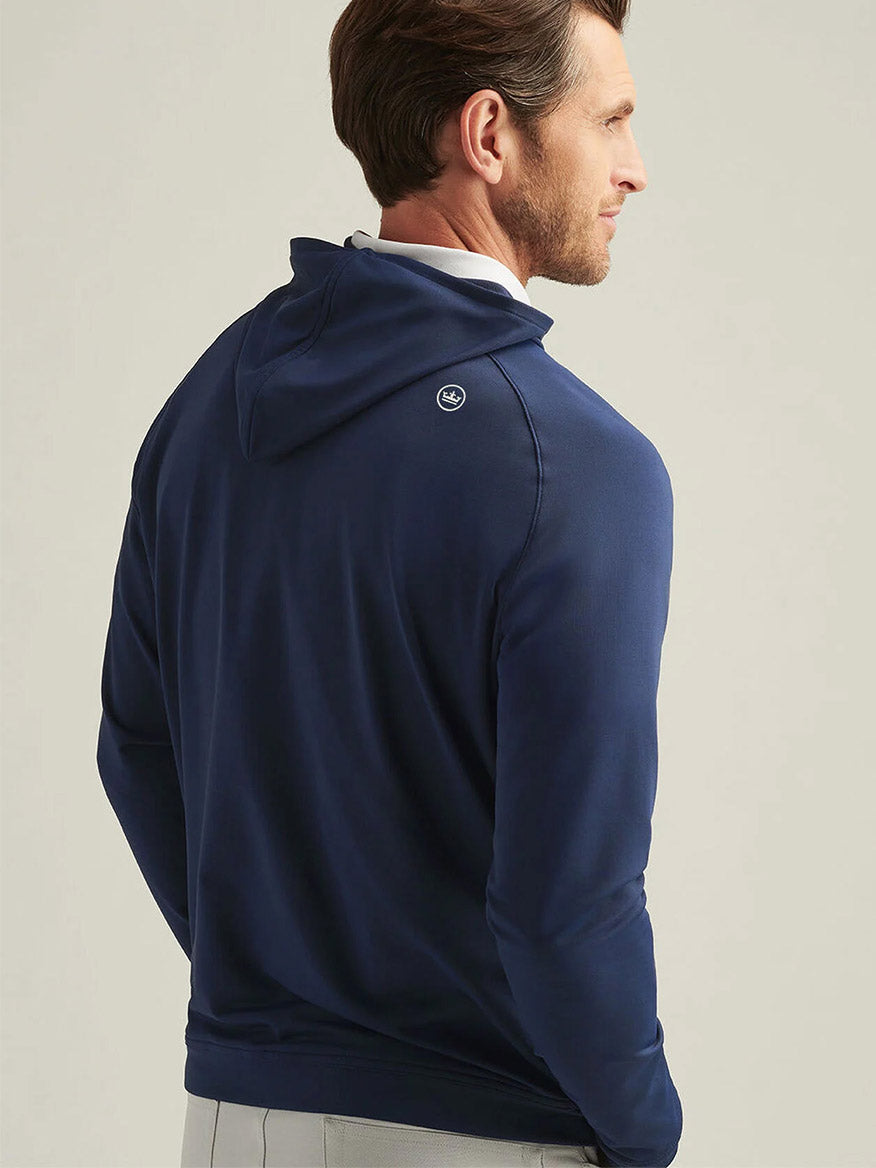 A man is seen from behind wearing the Peter Millar Pine Performance Hoodie in Navy, featuring a small round logo near the right shoulder and crafted from breathable fabric for all-day comfort.