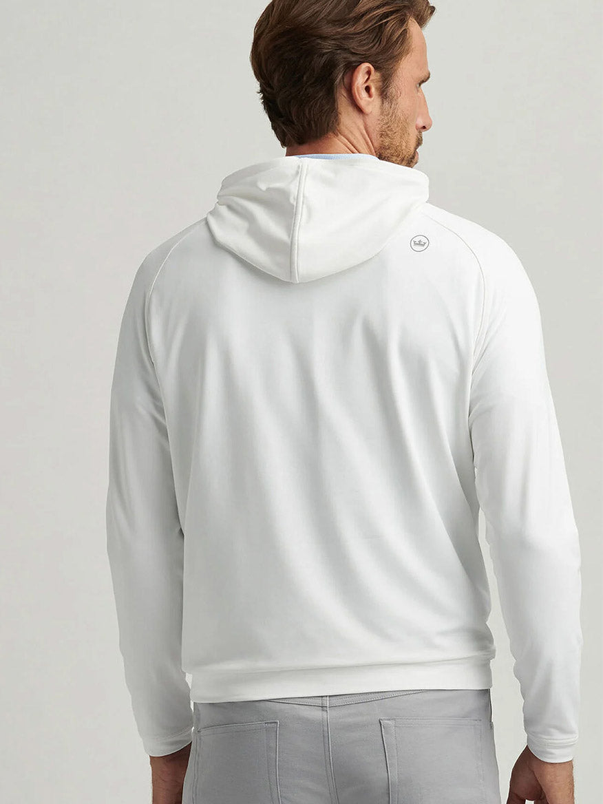 A man is shown from the back wearing a Peter Millar Pine Performance Hoodie in White and light gray pants with classic casual style against a plain background.