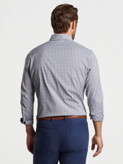 A man with short hair is seen from the back wearing a Peter Millar Prairie Performance Twill Sport Shirt in Galaxy, blue pants, and a brown belt, standing against a plain white background.