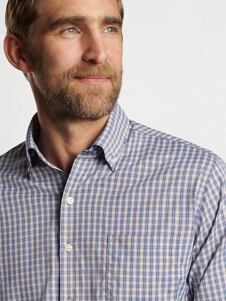 A man with a beard wearing the Peter Millar Prairie Performance Twill Sport Shirt in Galaxy, known for its easy-care performance fabric, looks into the distance.