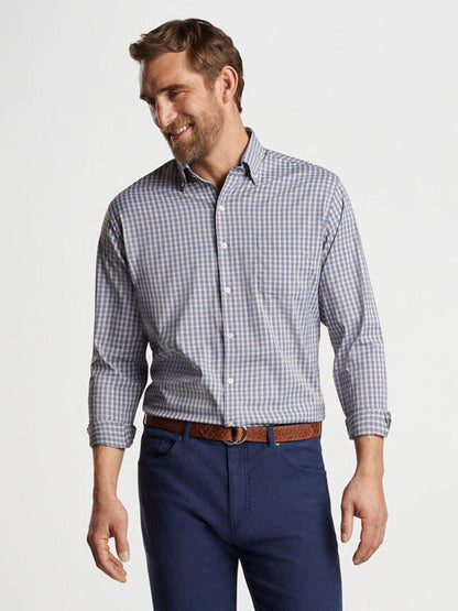 A man standing and smiling, dressed in a Peter Millar Prairie Performance Twill Sport Shirt in Galaxy and blue jeans.