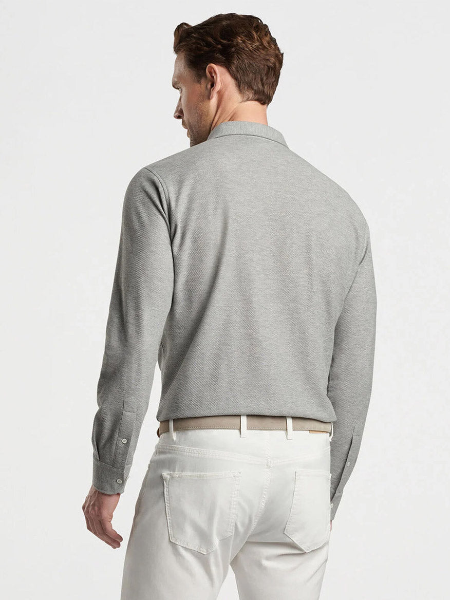 Man wearing a Peter Millar Ramble Long-Sleeve Cotton Cashmere Polo in Gale Grey and white pants facing away.